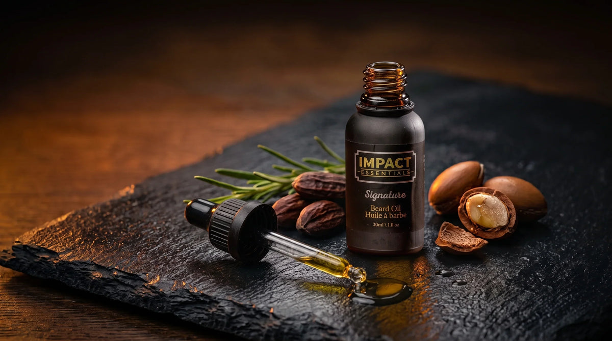  Natural beard oil - Amber dropper bottle standing on dark slate with raw botanical seeds and golden oil droplet.