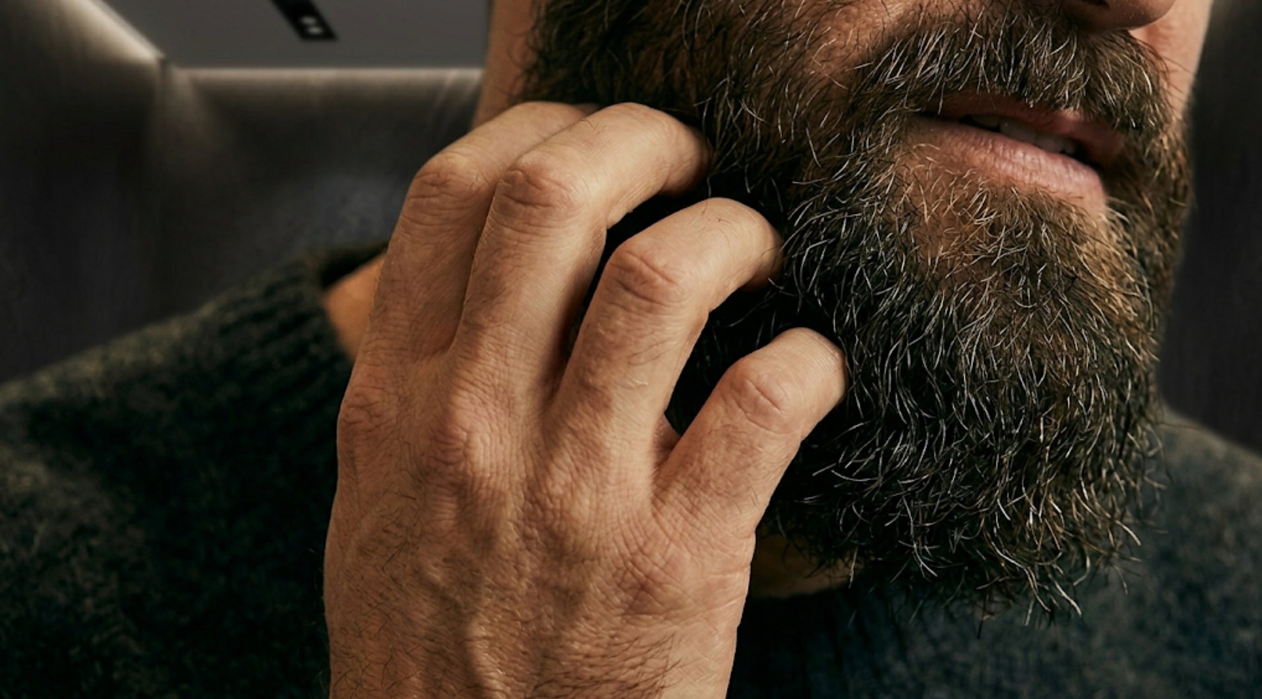 A close-up, high-contrast shot of a man comfortably grooming his beard, symbolizing relief from beard itch.