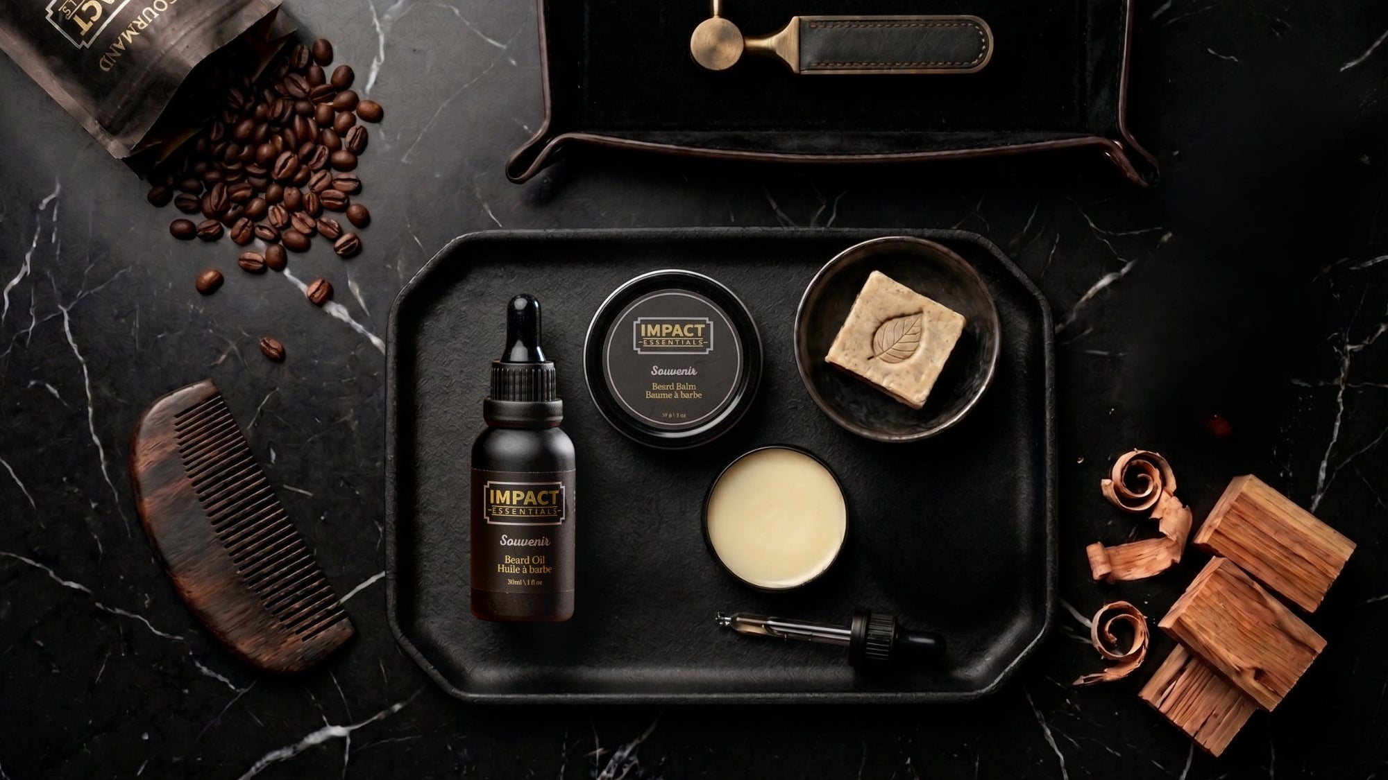 Set of beard grooming products on a black tray with coffee beans and wooden items on a dark surface.