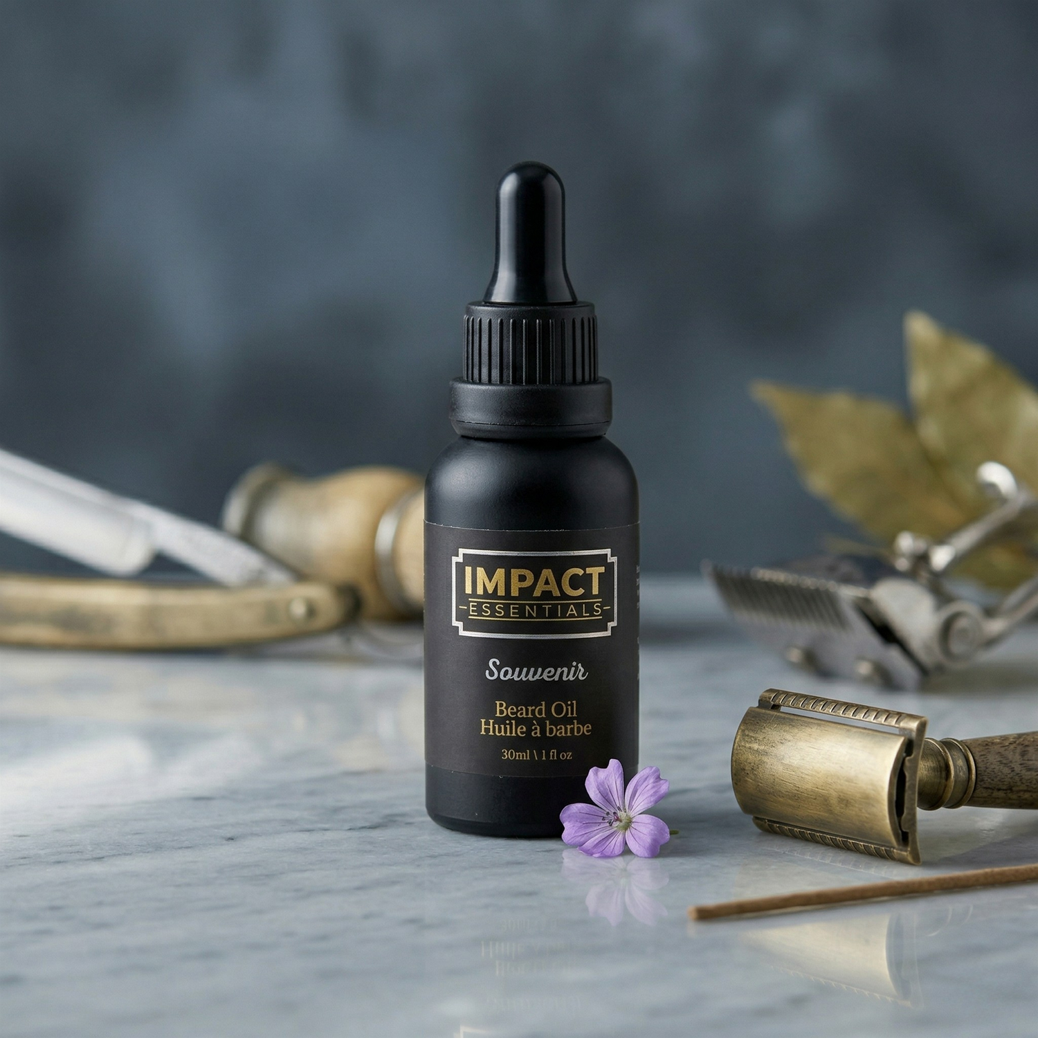 Beard oil bottle labeled 'Impact Essentials' with vintage razors and a flower on a marble surface.